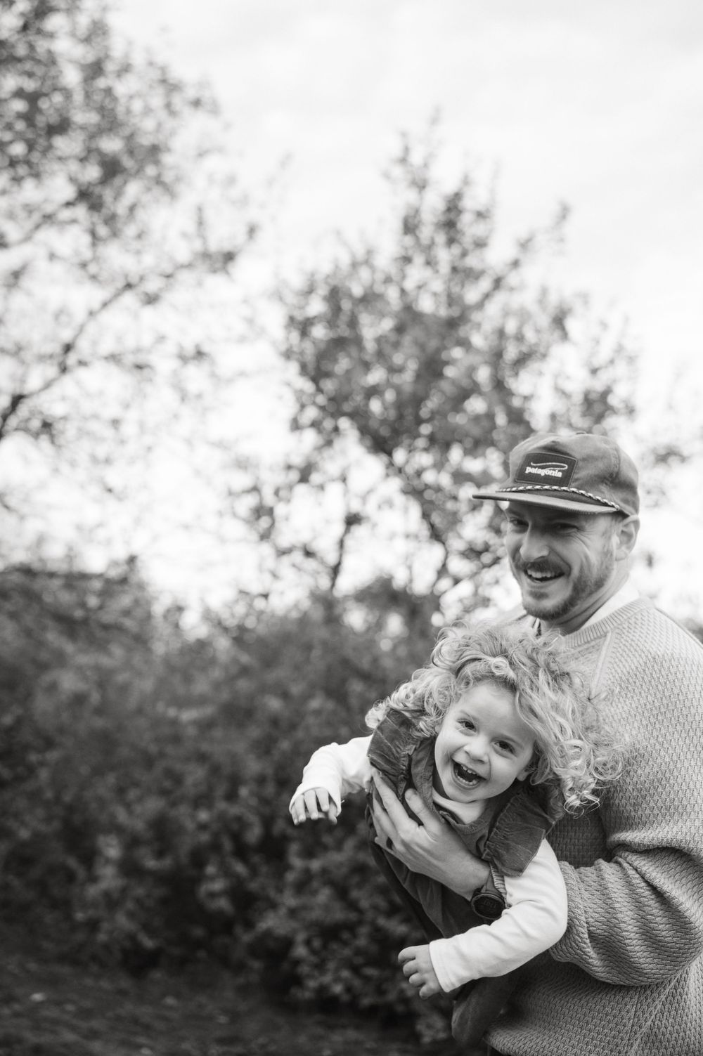 Black and white photo sequence showing joyful outdoor moments between a child and adult in a natural setting.