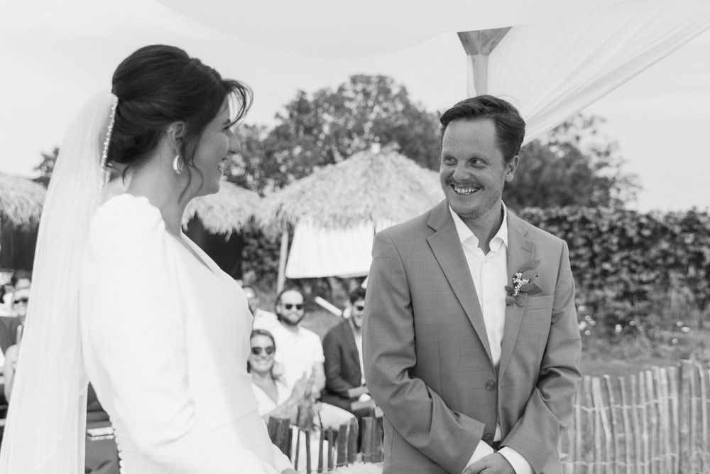 Black and white photo capturing a heartfelt moment between a bride and groom during an outdoor wedding ceremony.