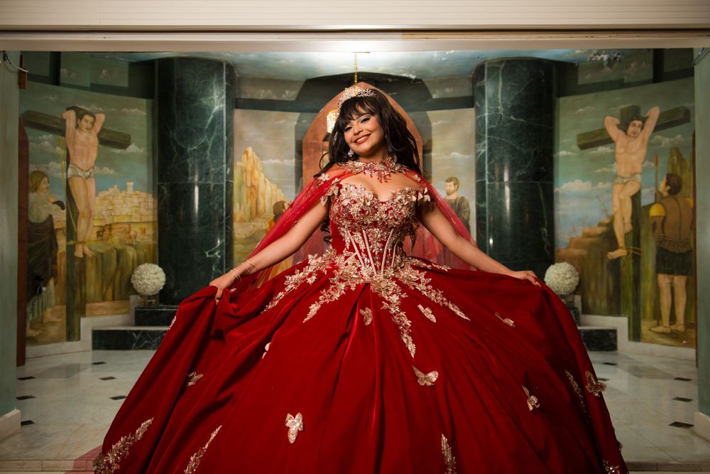 Embellished red formal dress shown twirling in an elegant marble-floored hall.