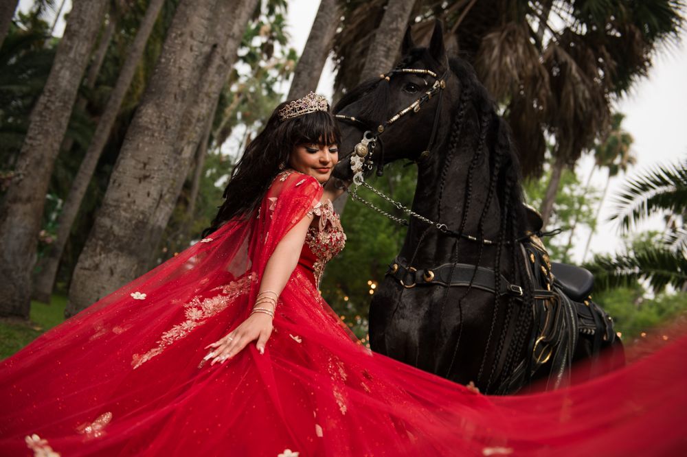 Flowing red dress captured in motion beside large black equestrian statue.