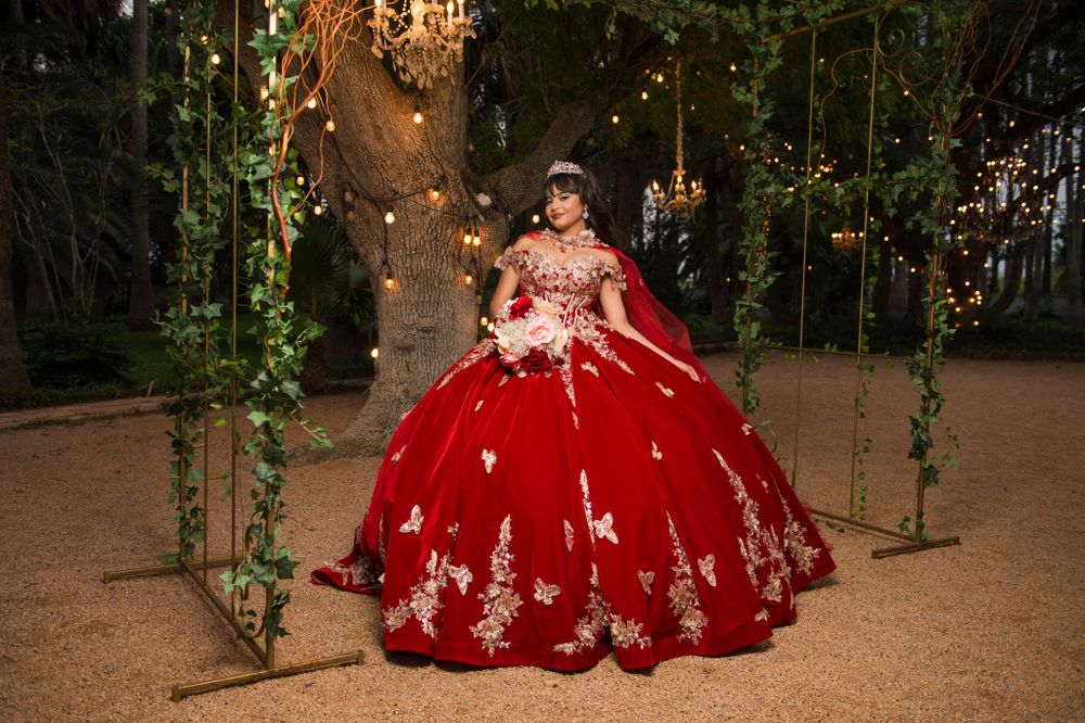 Ethereal forest scene with a red ballgown surrounded by hanging lights and greenery.