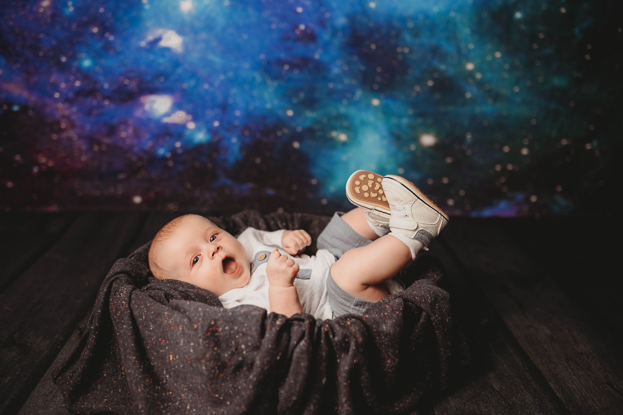 Baby portrait session with dreamy cosmic galaxy background and twinkling stars.