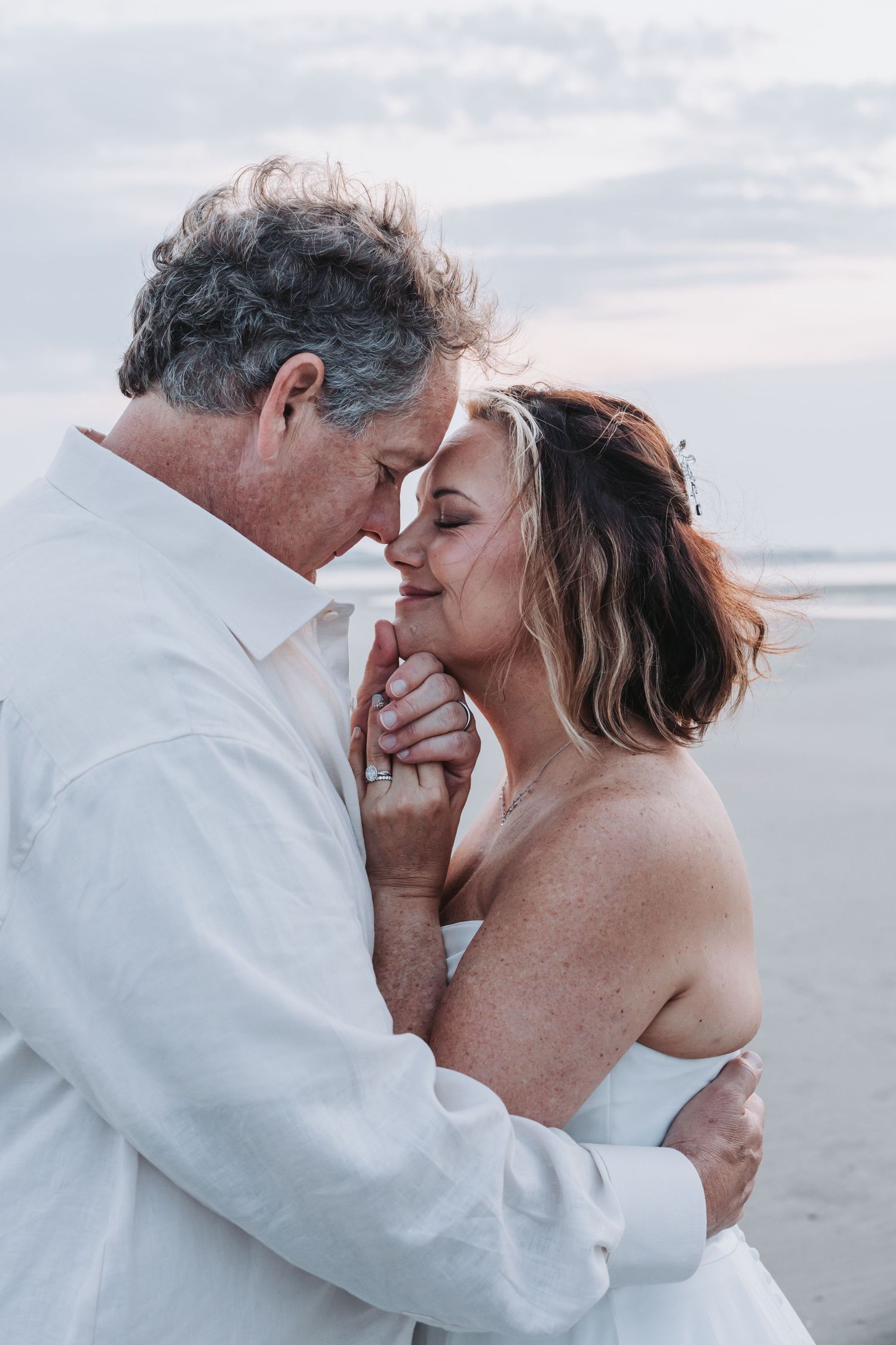 Couple shares tender moment during golden hour photography session by the water.