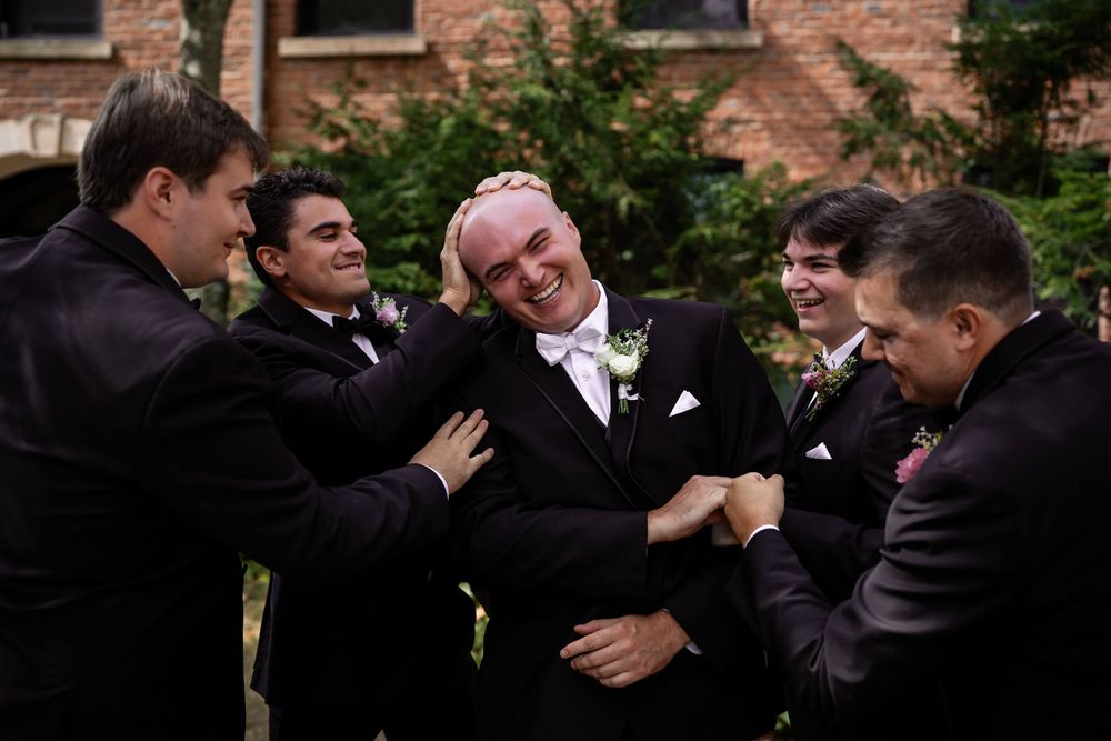 A sequence of candid moments showing groomsmen in black tuxedos sharing laughter and embraces outdoors.