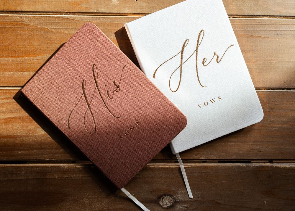 Wedding invitation cards in white and rose brown colors arranged on a wooden table.