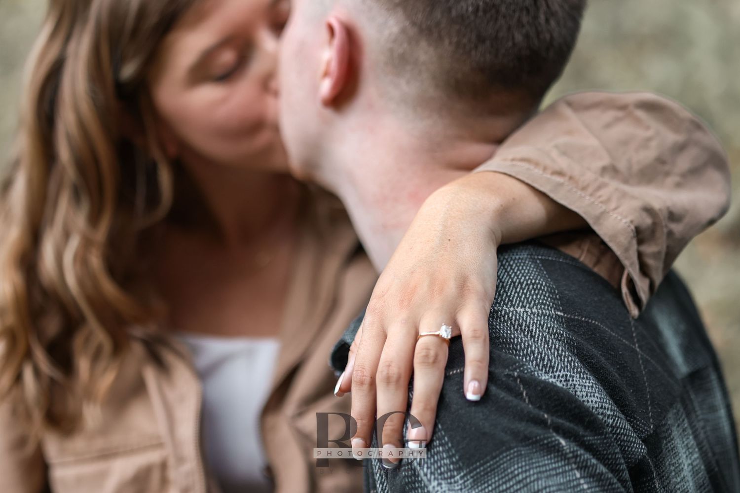 Close up of an engagement ring as couple shares intimate moment outdoors.