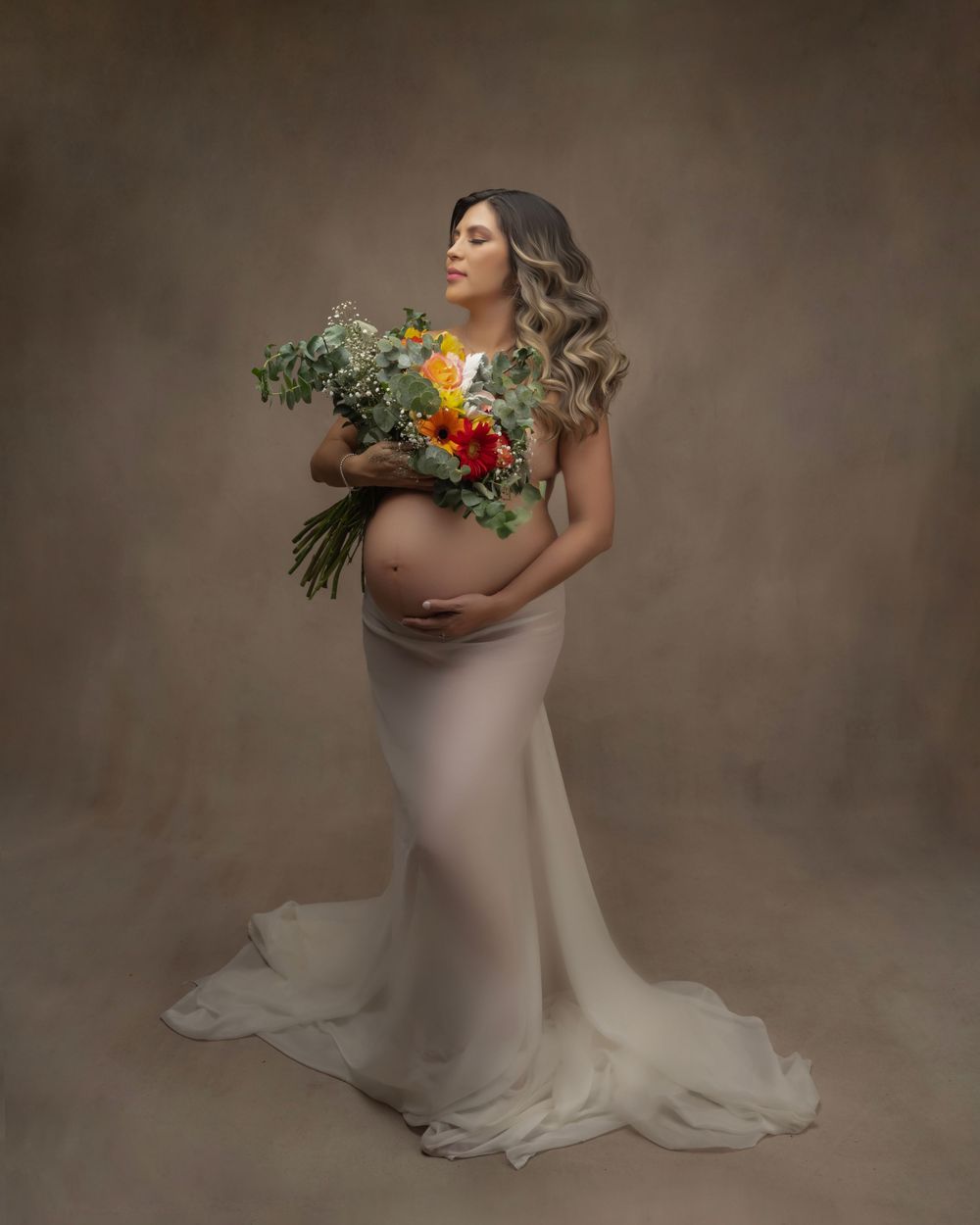 Artistic maternity portrait with colorful bouquet and fitted white gown.