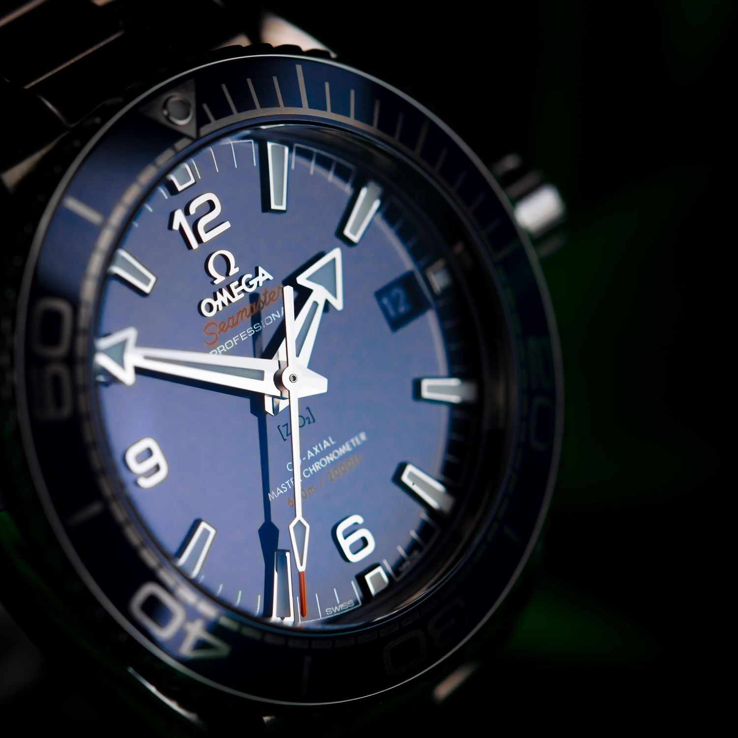 Close-up of an Omega watch face showing luminous hands and numbers against a dark blue dial background.