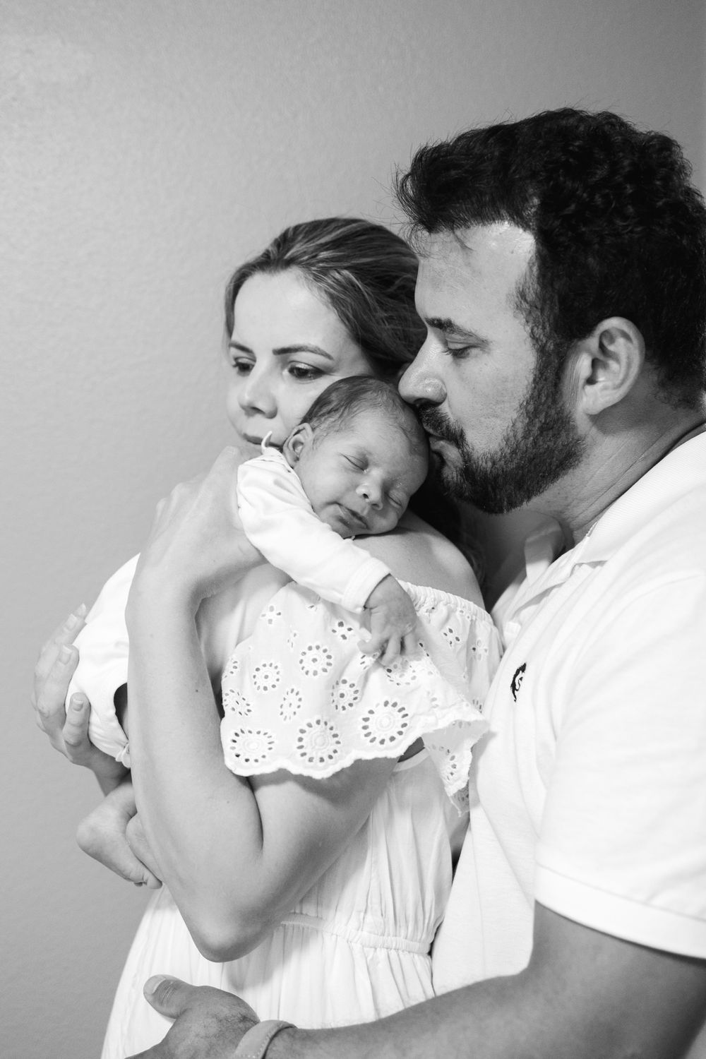 A series of black and white photos showing tender moments between a parent and child in white clothing.