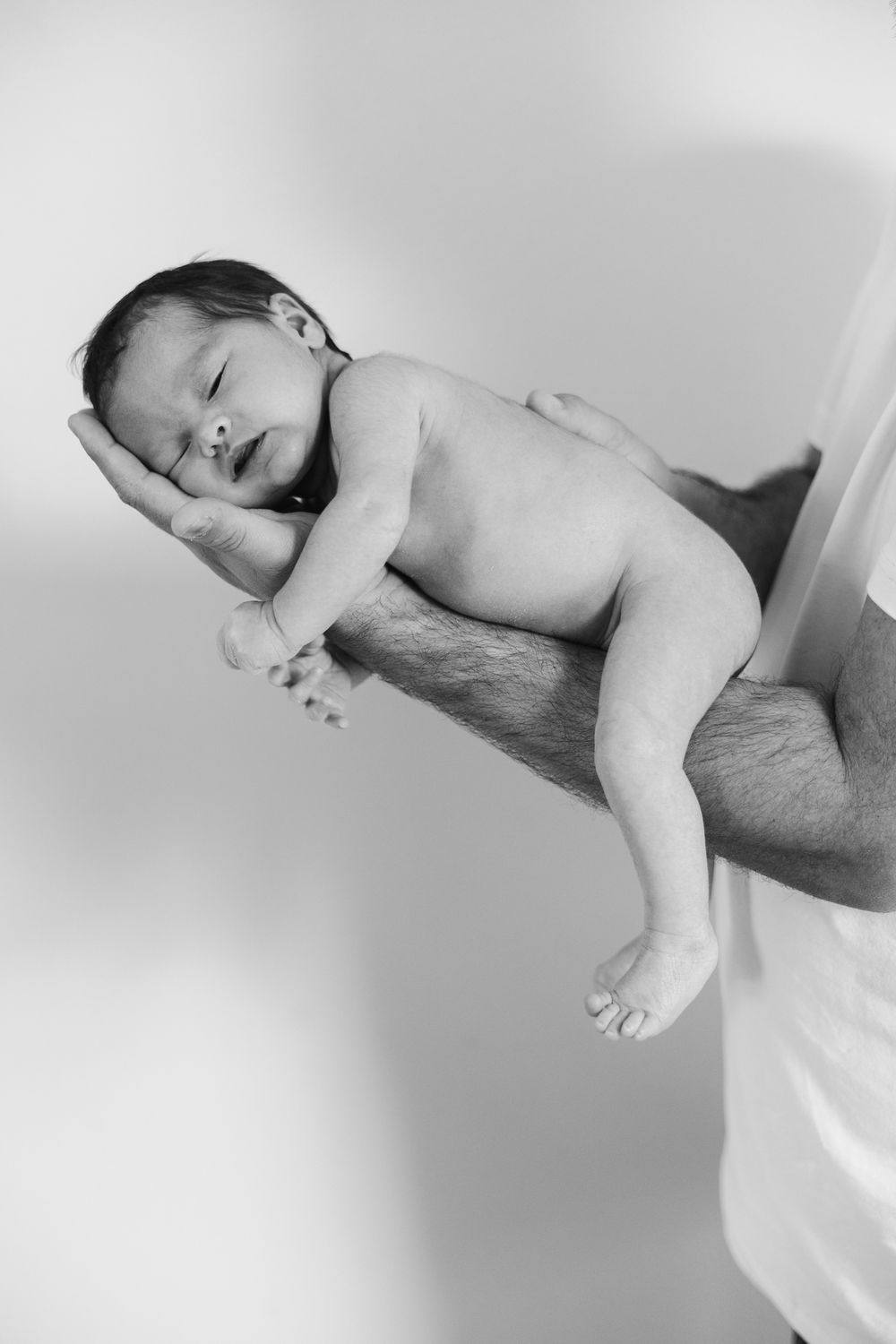 A sleeping baby lies peacefully on white bedding in black and white tones.