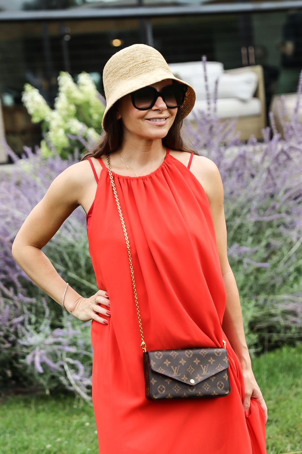 Outdoor winery fashion scene with red dress and accessories against purple flowers.