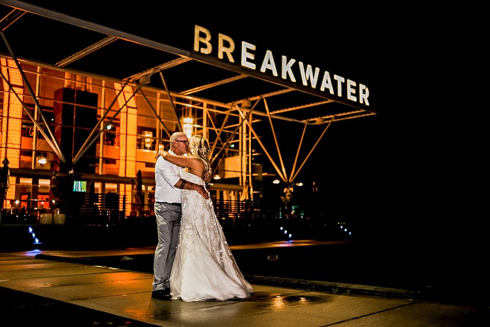 Evening wedding portrait under illuminated Breakwater sign with elegant formal attire.Jasper SkyTram