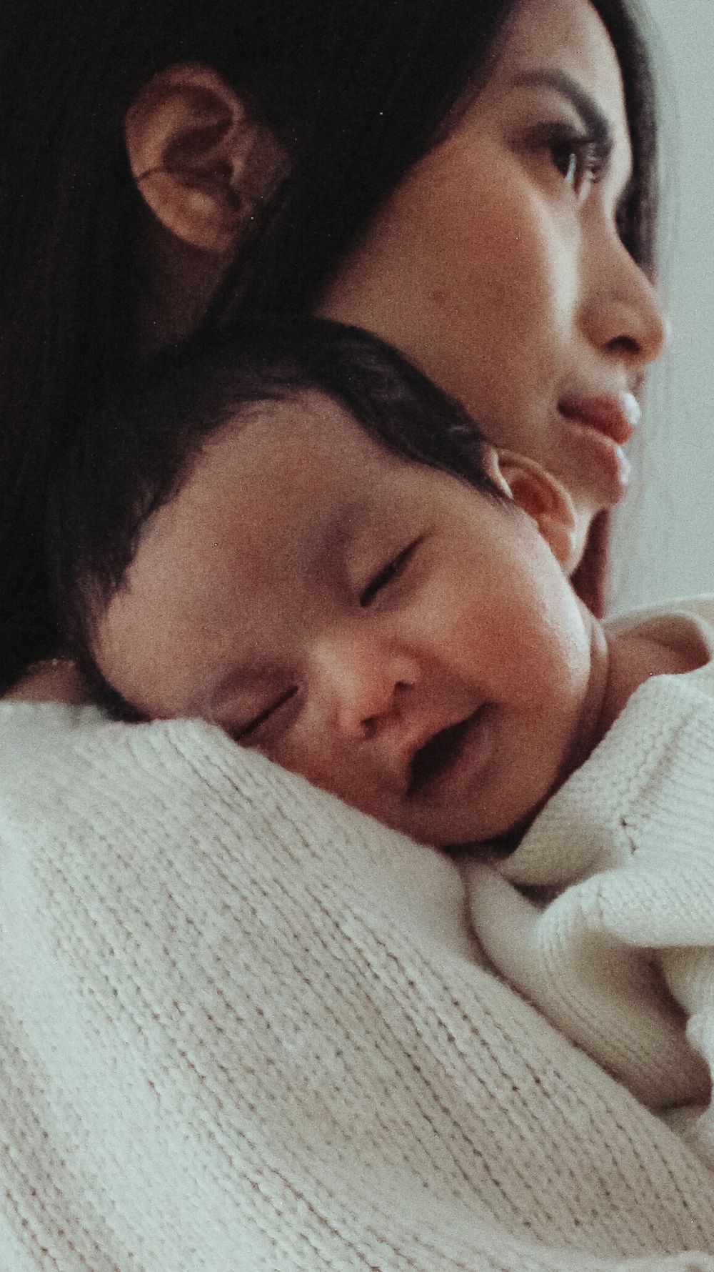sleepy newborn snuggles and smiles with mom