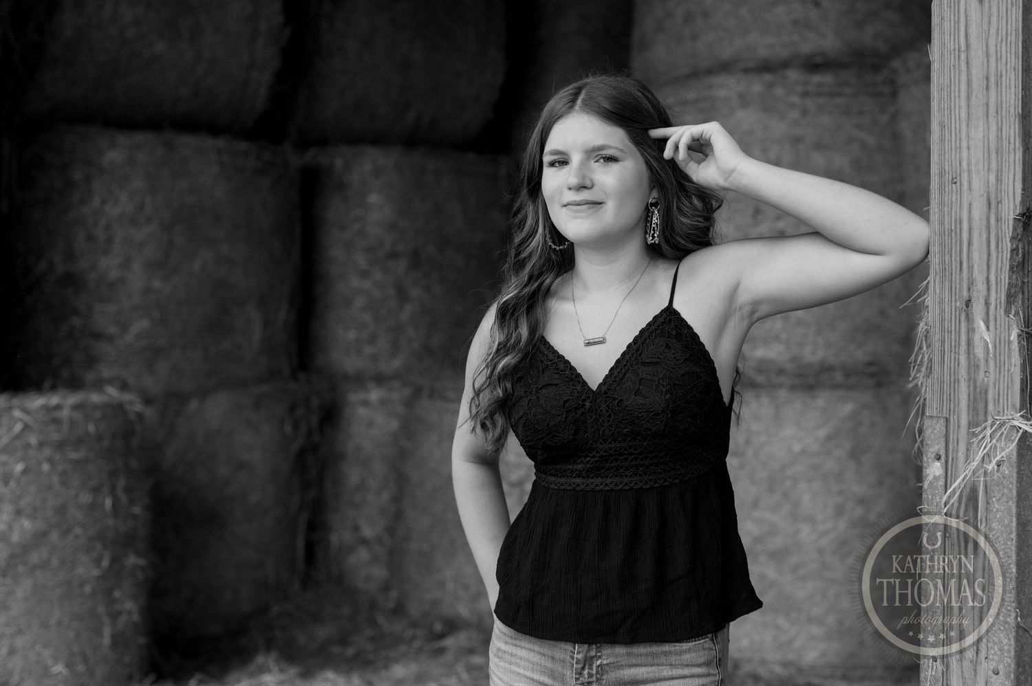 Black and white portrait of casual pose against barn hay bales.