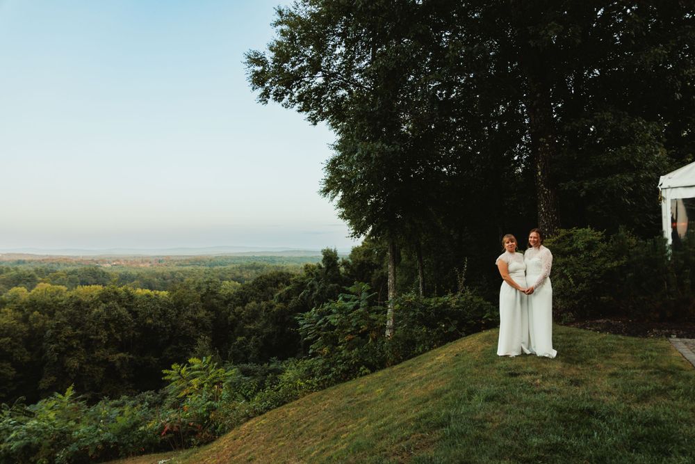 Scenic hilltop wedding photo with rolling landscape views in the background.