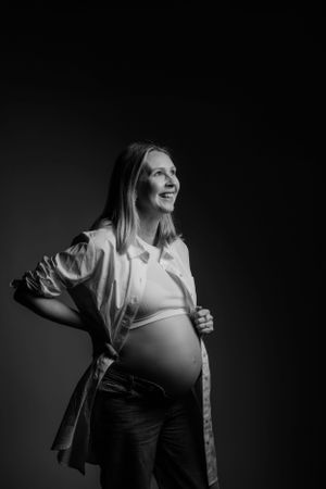Zwart-wit portret van een aanstaande persoon in een wit button-down overhemd poserend tegen een donkere achtergrond.