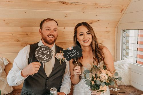 A happy couple holding 'Better Together' signs at their rustic barn wedding celebration captured by wedding videographer Jovan Films.