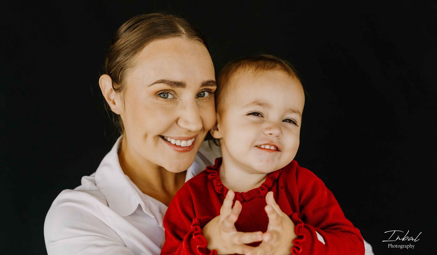 A mother holding her little girl while looking at the camera, capturing their warm and intimate connection.