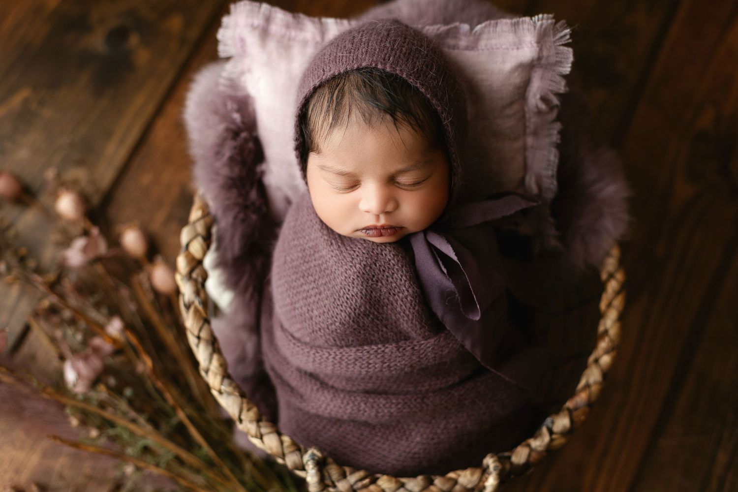 Beautiful Indian newborn baby girl in soft purple wrap and a bonnet to match. Baby has dark beautiful hair. Greenville, SC Photographer