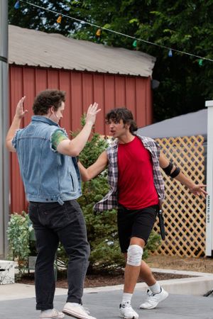 Two people engaging in an animated interaction outdoors with string lights visible in background.