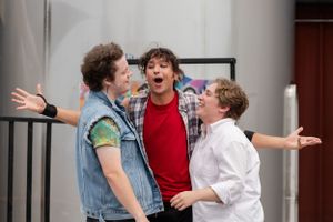 Three performers express dramatic emotions during a theatrical scene.