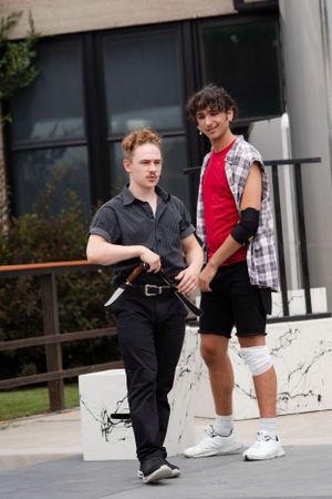 Two casually dressed people stand together on steps outside a building.