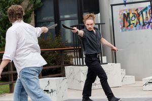 Two performers face off in a dramatic confrontation on an outdoor stage.