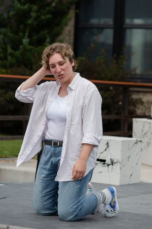 A performer in casual attire poses dramatically on an outdoor stage platform.