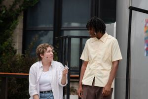 Two young people having a casual conversation outside a building on a sunny day.