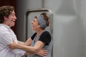 Two people share a joyful moment while embracing, with one wearing a grey headband and dark shirt.