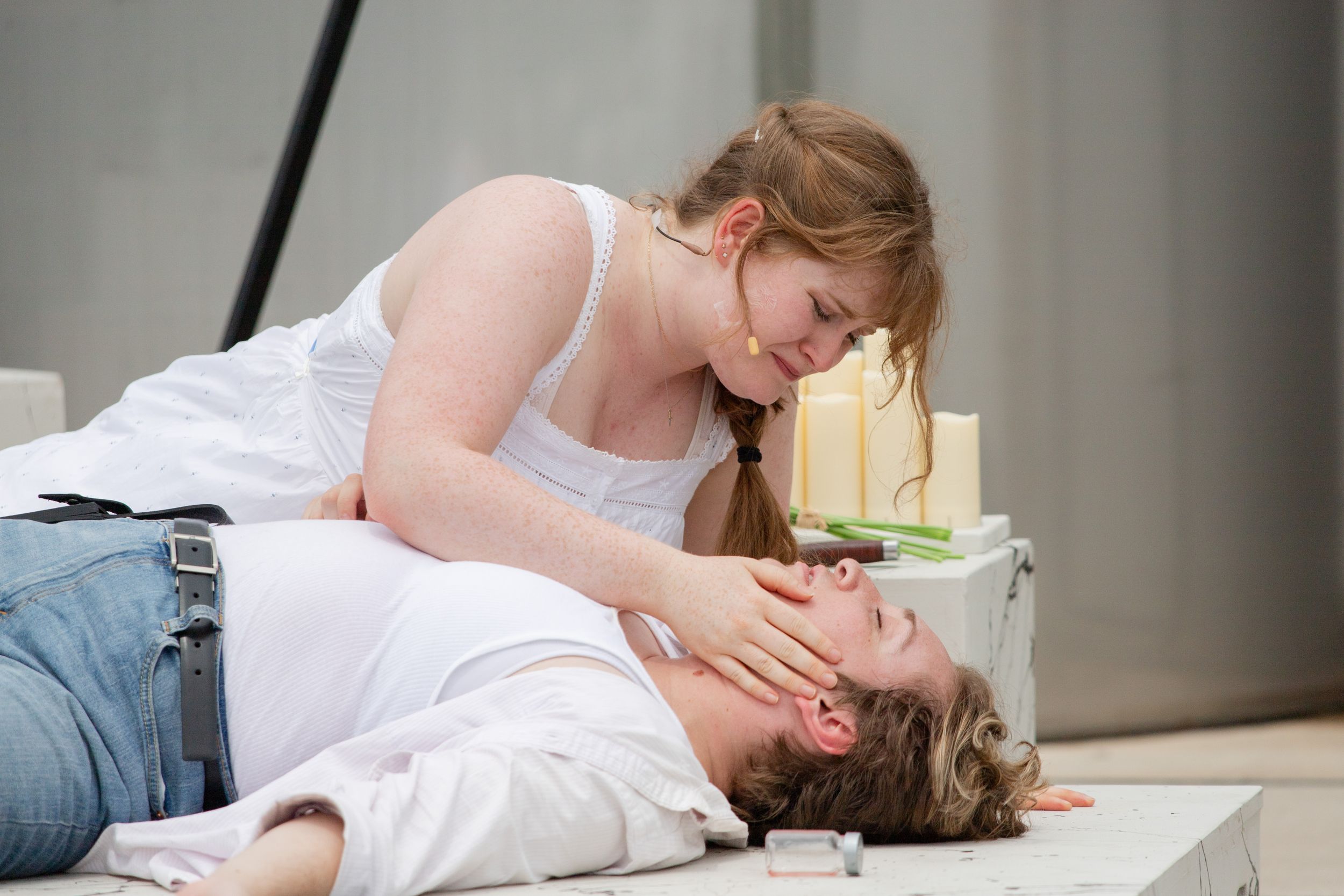Two people share an intimate moment lying on a light colored floor.