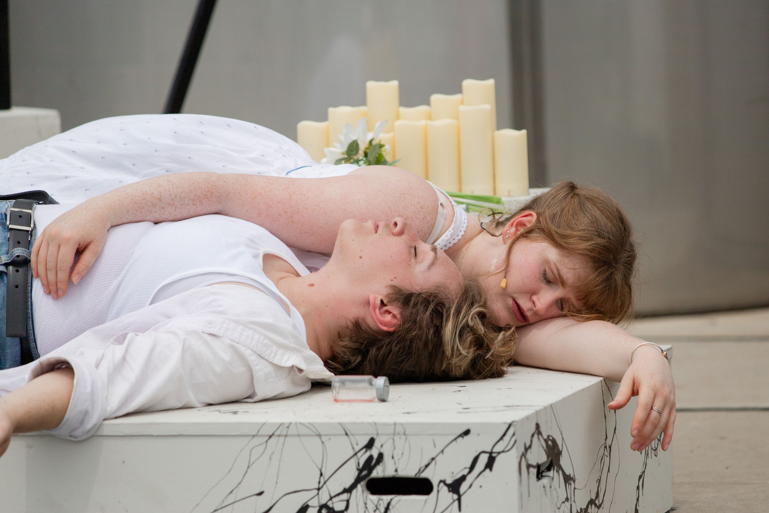 A couple lying close together on a light colored surface, sharing an intimate relaxed moment.