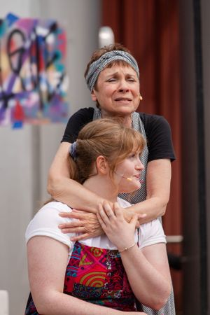 Two performers share an intimate dramatic moment during an outdoor theatrical scene.