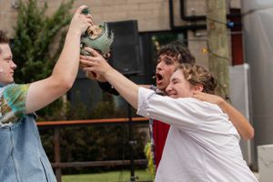 Two people in a garden energetically reach up with their arms in an animated playful moment outdoors.