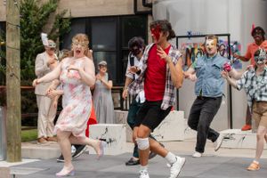 A group of performers dance and move energetically during an outdoor performance.