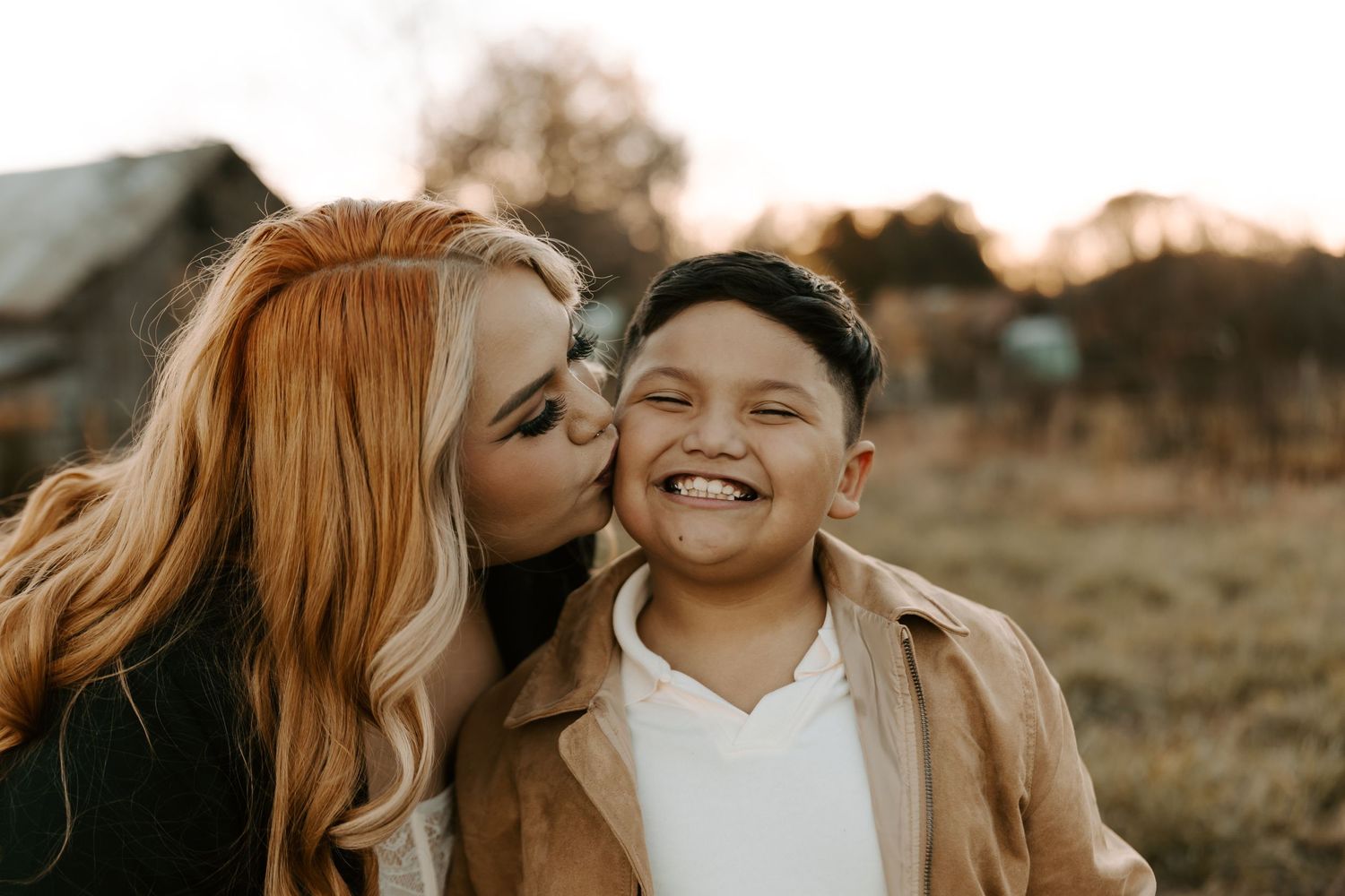 Sweet moment between parent and child with genuine laughter in warm sunlight.