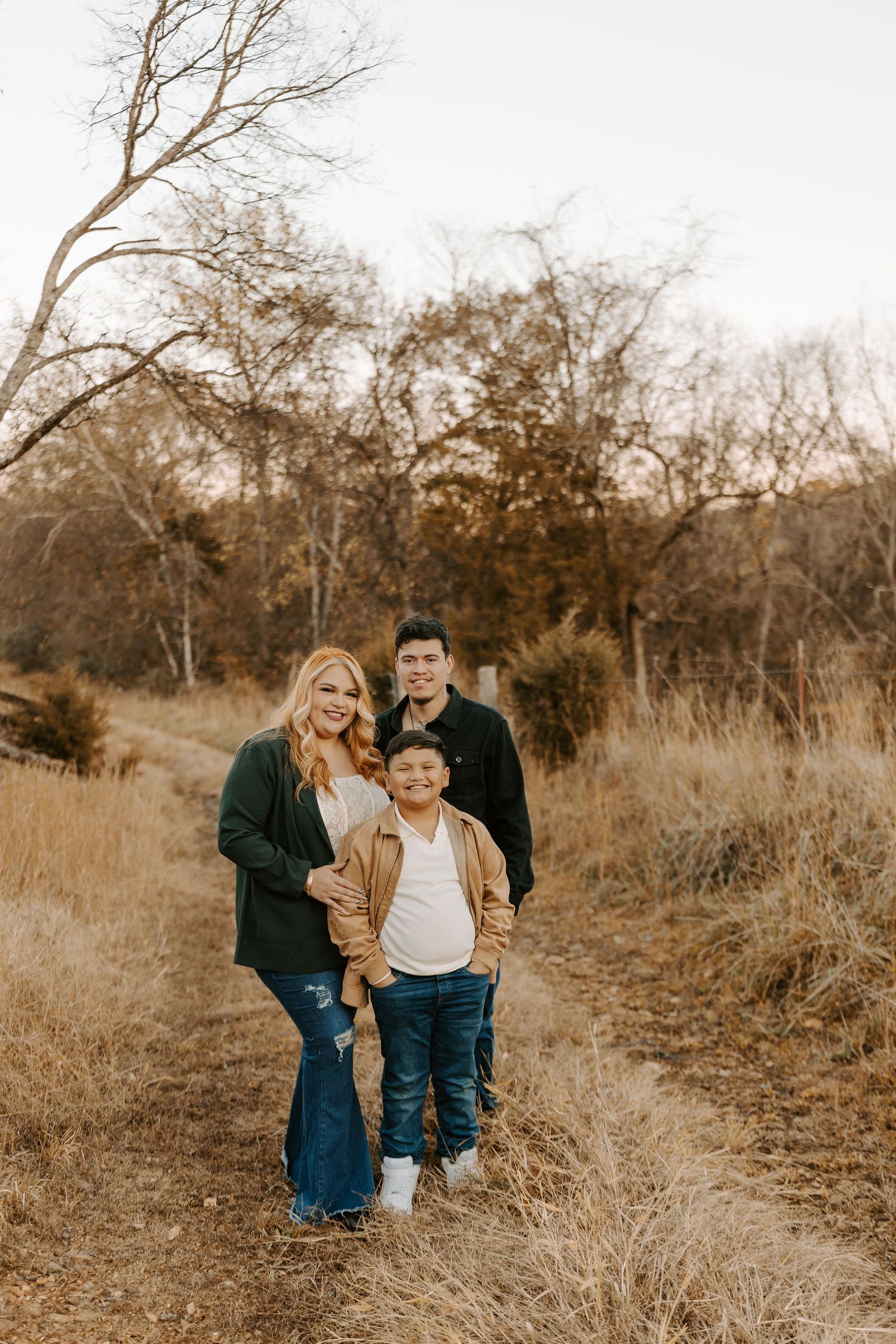 Family portrait on a nature trail surrounded by autumn foliage and golden light.