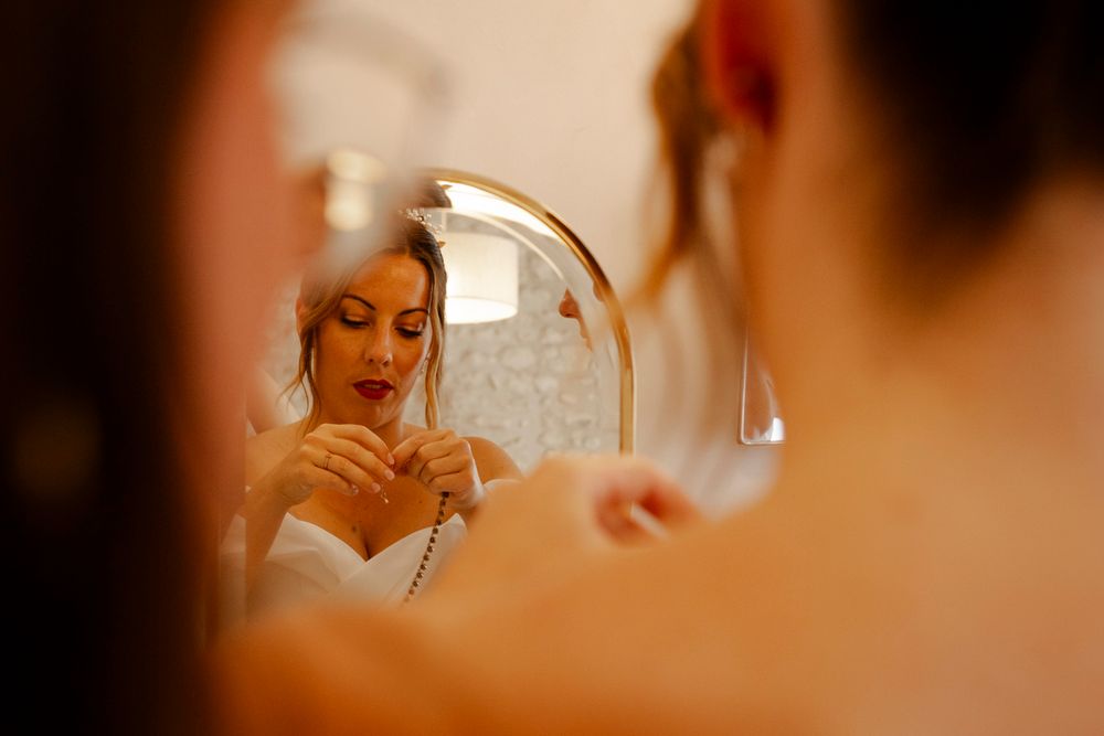 mariée mettant ses bijoux à travers un miroir