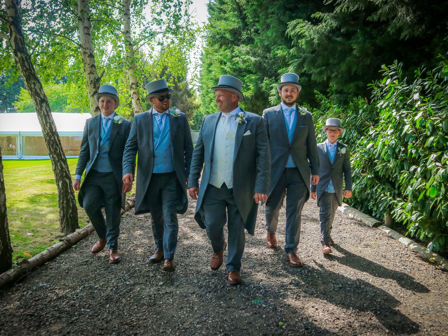 Group walking together on tree-lined path wearing coordinated blue outfits.
