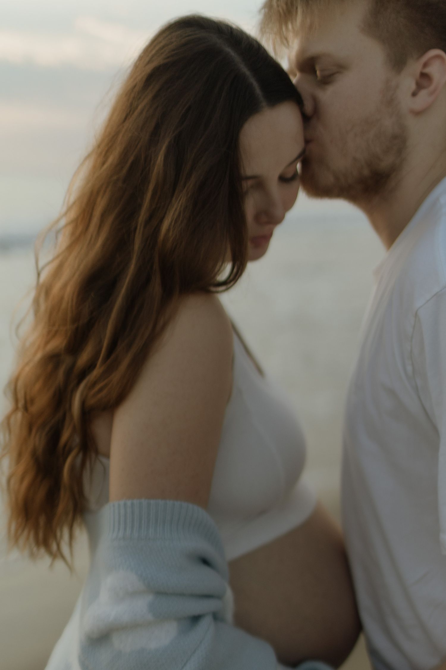 A romantic couple shares an intimate moment at sunset with soft lighting and dreamy atmosphere.