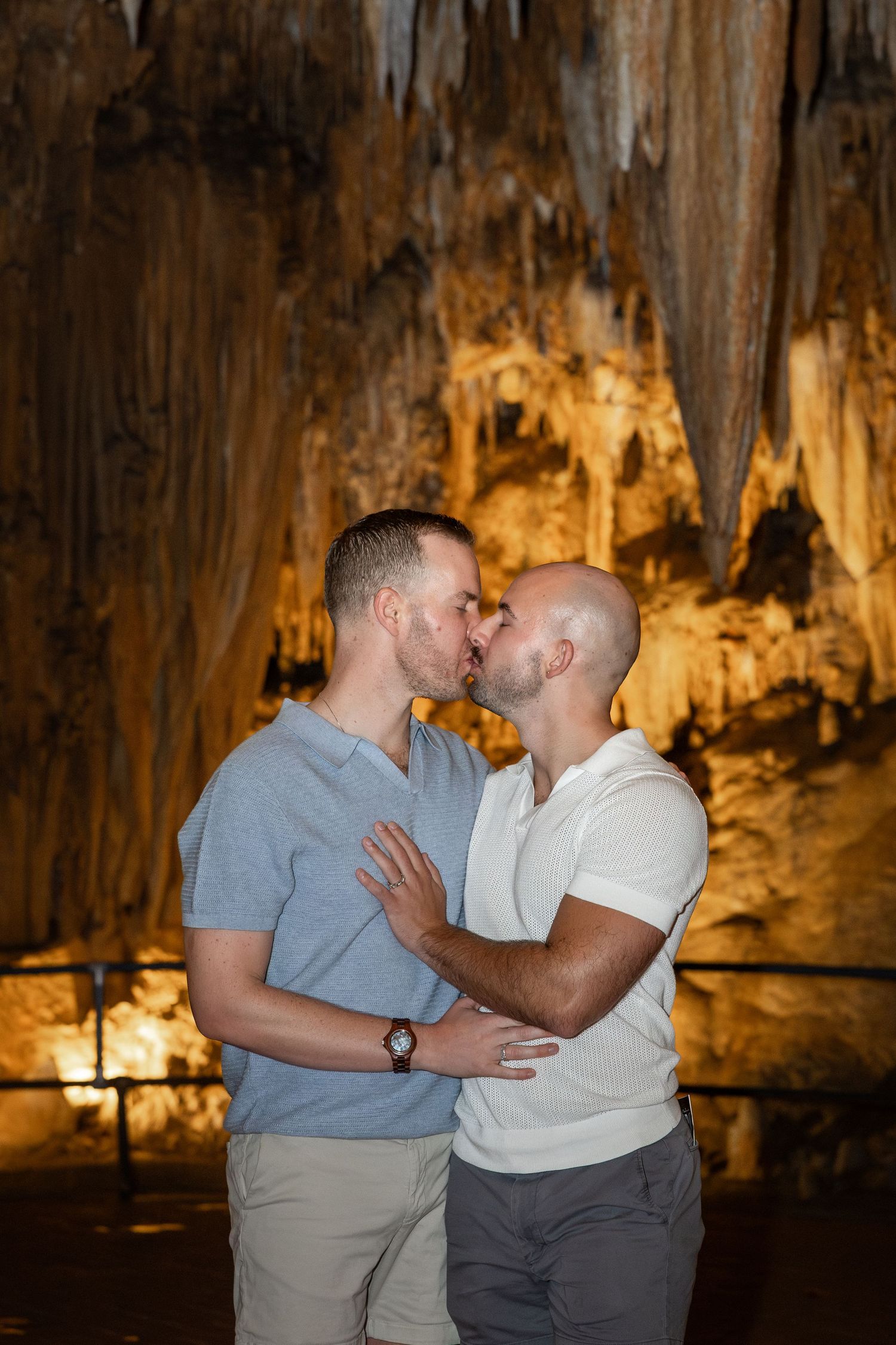 A romantic moment shared between a couple in a dimly lit cave with illuminated stalactites and rock formations.