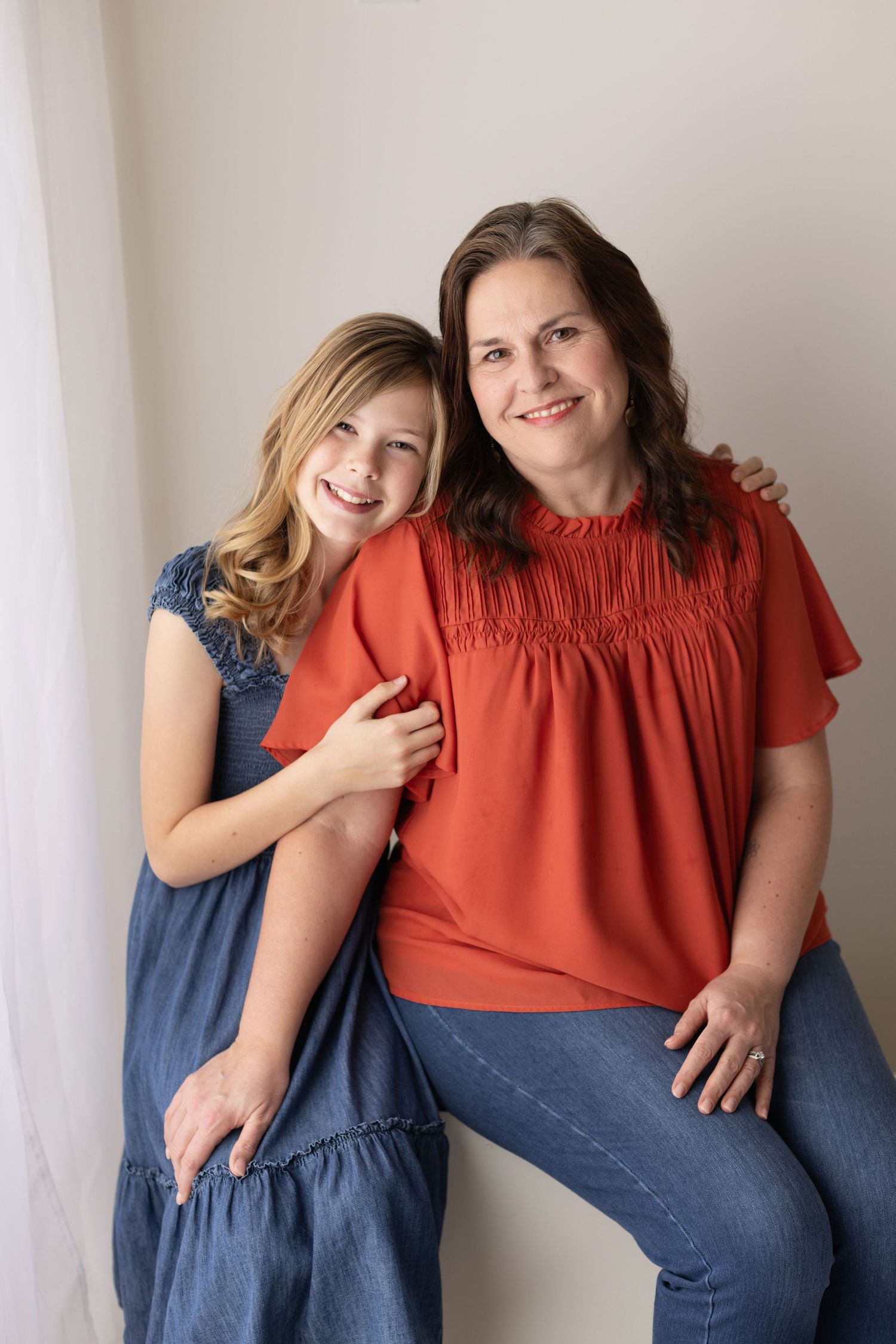 A parent and child share a candid moment while posing in complementary coral and denim outfits. Elizabeth Lang Photography Surrey