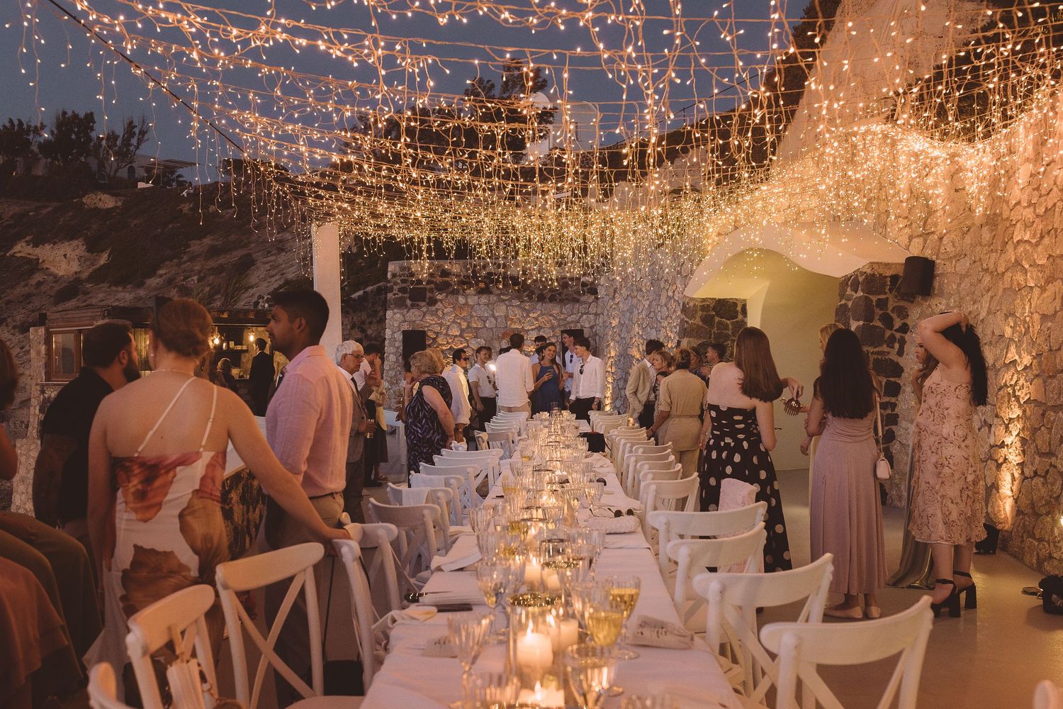 Destination wedding reception venue decorated with twinkling string lights and candles on El Viento veranda in Santorini.