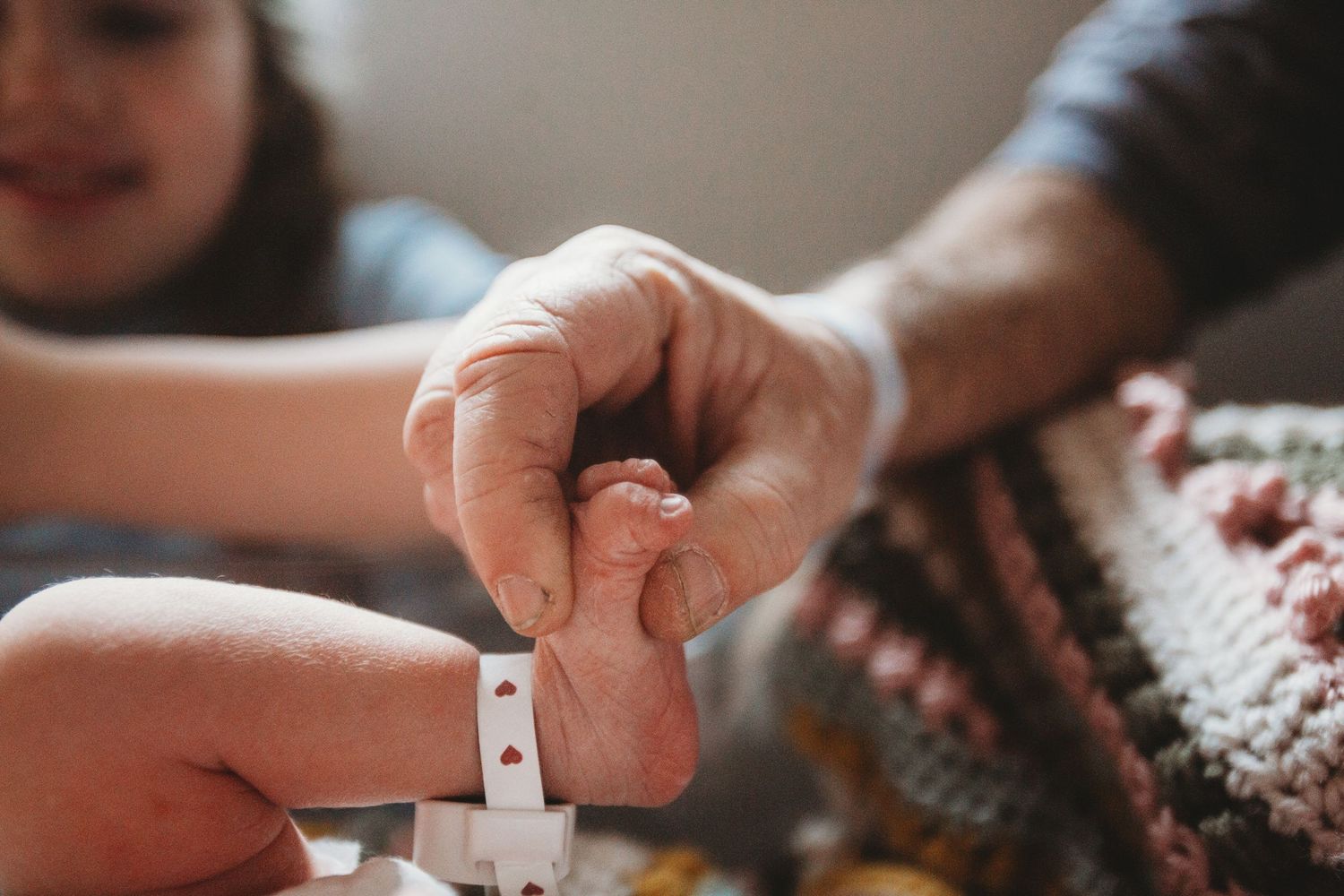 Close-up view of hands working on a jigsaw puzzle with pieces scattered on a wooden surface.