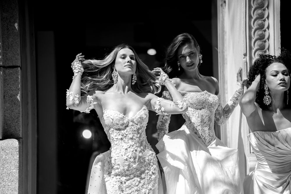 Black and white photo of women in elegant bridal gowns posing together in a stylish fashion shoot.