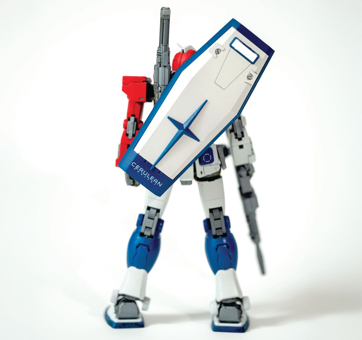 A toy robot figure in white, red and blue colors with a shield-like component stands against a white background.