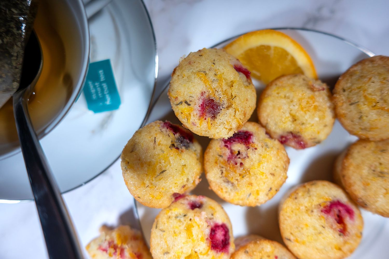 Fresh cranberry orange muffins with chocolate cookies arranged on a white plate.