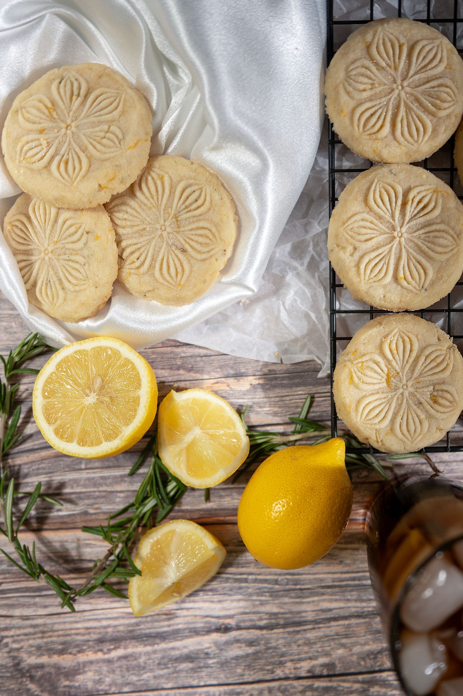 Homemade shortbread cookies with lemon slices and fresh rosemary on rustic wooden background.