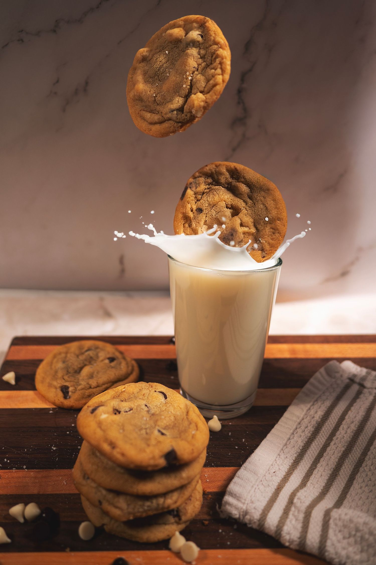 A sequence showing a chocolate chip cookie splashing into a glass of milk creating a dynamic splash effect.