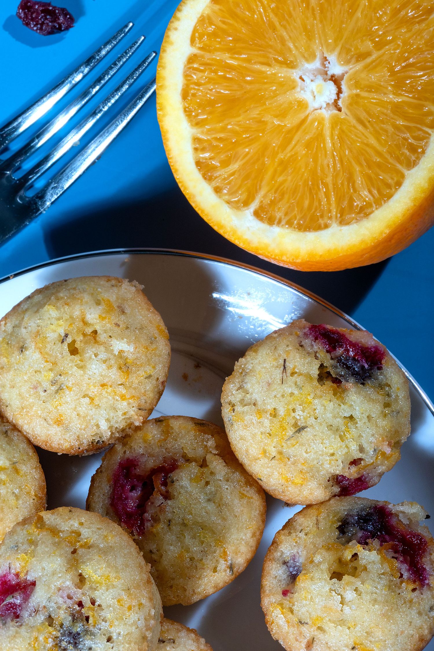 Fresh orange slices and homemade cranberry cookies on a blue background create a bright, appetizing display.